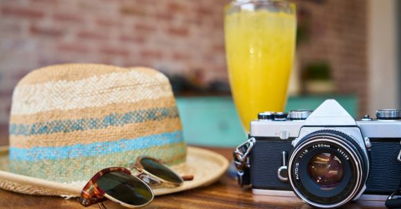Stylish Vacation Essentials - Gray and Black Dslr Camera Beside Sun Hat and Sunglasses